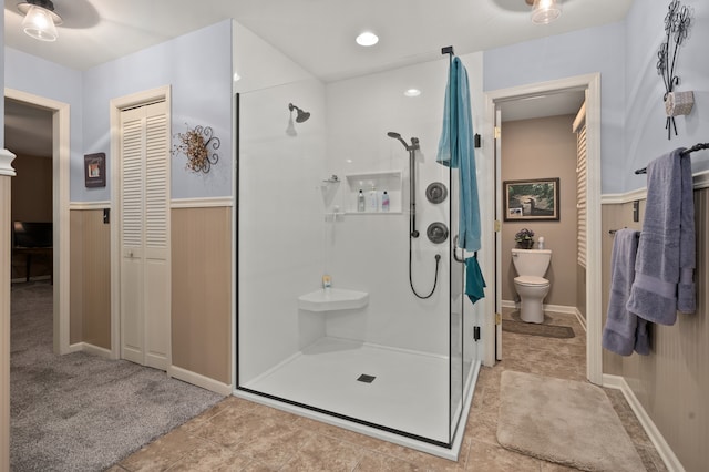 bathroom featuring a shower with door, tile patterned floors, and toilet