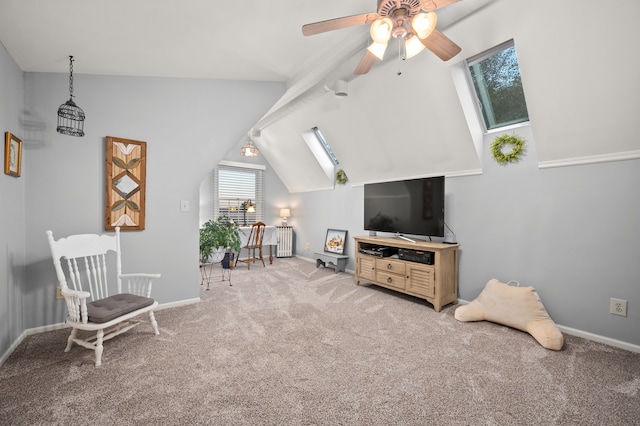 living area featuring vaulted ceiling with skylight, radiator heating unit, light carpet, and ceiling fan