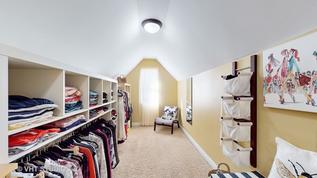 walk in closet with light carpet and lofted ceiling