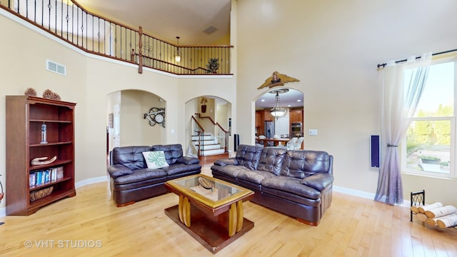 living room with light hardwood / wood-style floors and a high ceiling