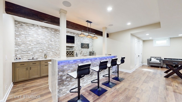 bar with beam ceiling, decorative columns, pendant lighting, and light hardwood / wood-style floors