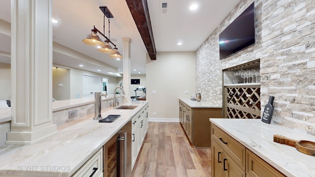 kitchen with sink, light hardwood / wood-style flooring, light stone counters, and decorative light fixtures