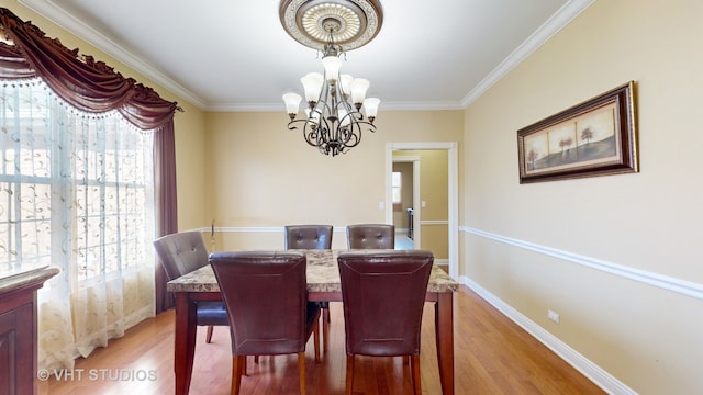 dining area with crown molding, a notable chandelier, and light wood-type flooring