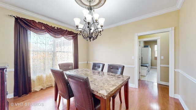 dining space with crown molding, light hardwood / wood-style flooring, and a notable chandelier