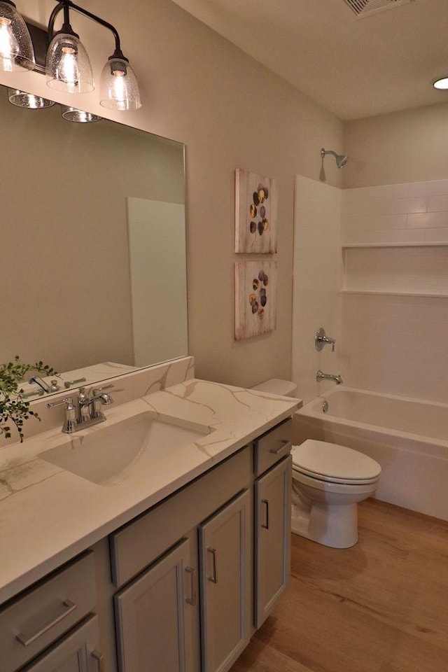 full bathroom with hardwood / wood-style flooring, vanity, shower / tub combination, and toilet