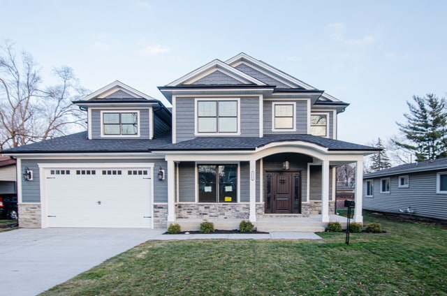 view of front of home with a front lawn, covered porch, and a garage