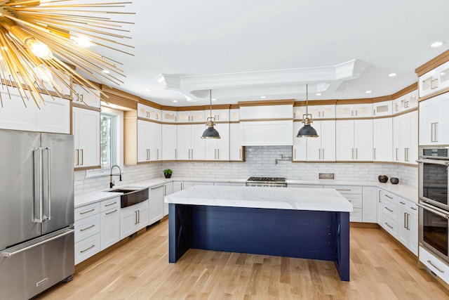 kitchen featuring appliances with stainless steel finishes, sink, a kitchen island, light hardwood / wood-style floors, and light stone counters