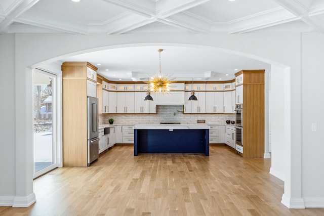 kitchen featuring a kitchen island, decorative light fixtures, light wood-type flooring, white cabinets, and tasteful backsplash