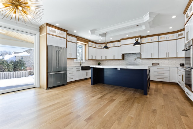 kitchen with a kitchen island, backsplash, high quality fridge, pendant lighting, and light hardwood / wood-style floors