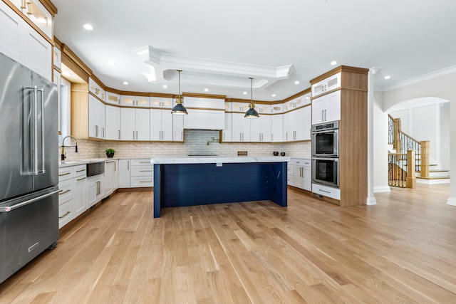 kitchen with appliances with stainless steel finishes, light wood-type flooring, white cabinetry, pendant lighting, and ornamental molding