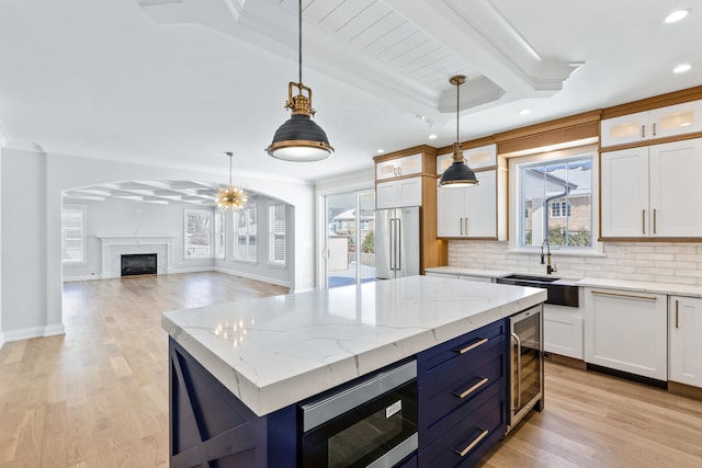 kitchen with a kitchen island, a healthy amount of sunlight, decorative light fixtures, white cabinetry, and appliances with stainless steel finishes