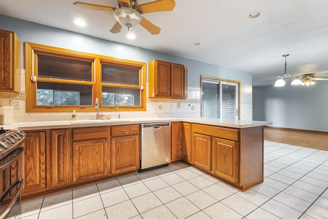 kitchen featuring stainless steel dishwasher, sink, kitchen peninsula, and backsplash