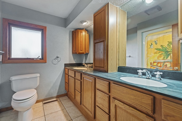 bathroom with vanity, toilet, a textured ceiling, and tile patterned flooring