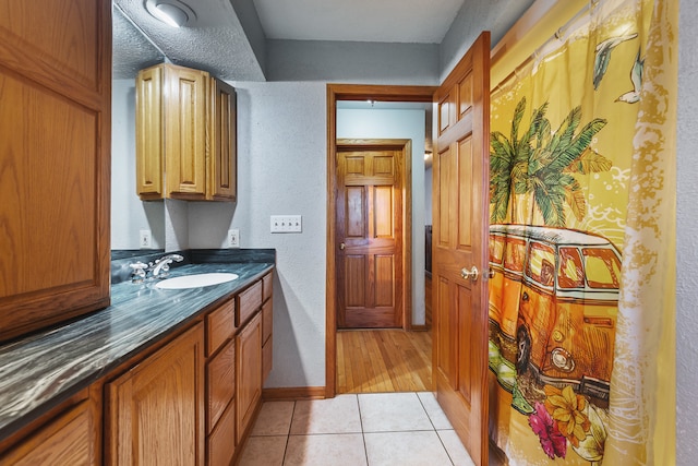 kitchen featuring dark stone countertops, light tile patterned flooring, sink, and a textured ceiling