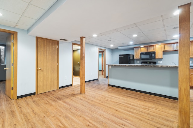 kitchen featuring kitchen peninsula, a paneled ceiling, light wood-type flooring, black appliances, and light stone counters