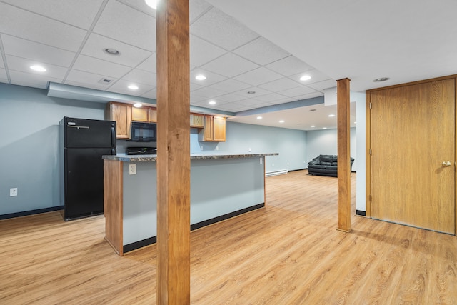 kitchen with black appliances, a drop ceiling, kitchen peninsula, and light wood-type flooring