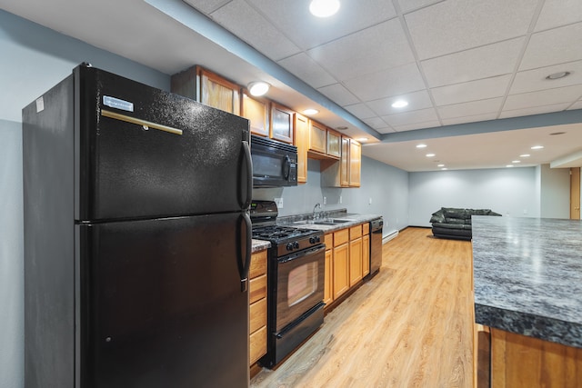 kitchen with light hardwood / wood-style floors, black appliances, sink, and a paneled ceiling