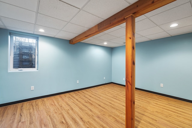 basement featuring a paneled ceiling and light hardwood / wood-style floors