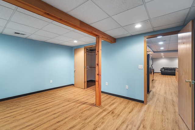 basement with a drop ceiling, light hardwood / wood-style floors, and black fridge