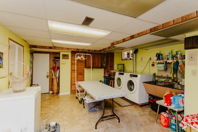 washroom with sink, independent washer and dryer, and light tile patterned flooring