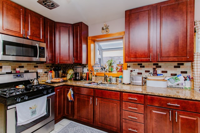 kitchen featuring sink, light tile patterned floors, appliances with stainless steel finishes, light stone counters, and tasteful backsplash