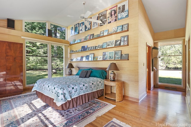 bedroom with high vaulted ceiling, multiple windows, wood-type flooring, and ceiling fan