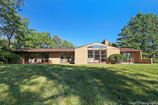 rear view of property featuring a yard and a sunroom