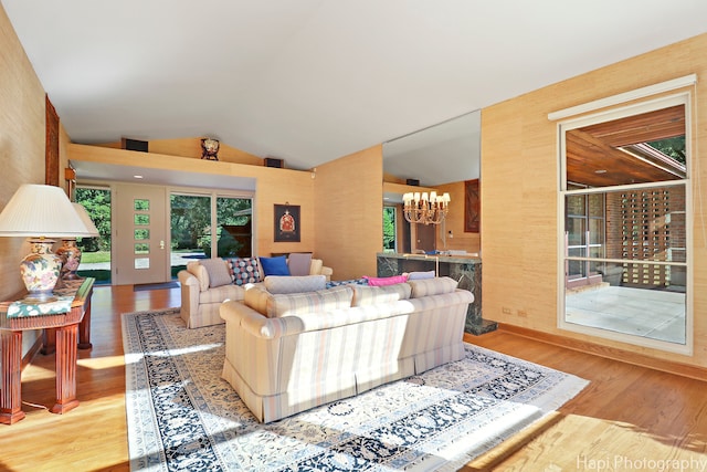 living room with a chandelier, vaulted ceiling, and light hardwood / wood-style flooring