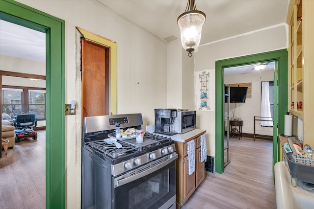 kitchen featuring ceiling fan, decorative light fixtures, light wood-type flooring, and stainless steel range with gas stovetop