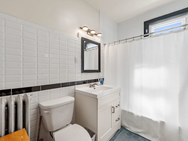 bathroom with toilet, radiator, tile walls, vanity, and walk in shower