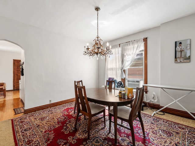 dining space with hardwood / wood-style floors, cooling unit, and an inviting chandelier