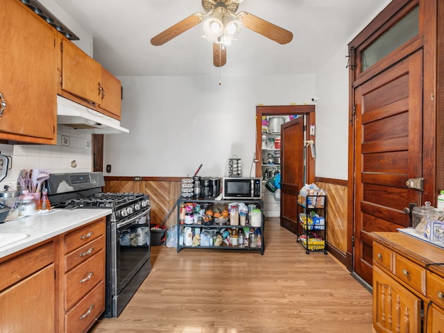 kitchen with black range with gas cooktop, ceiling fan, light wood-type flooring, and tasteful backsplash