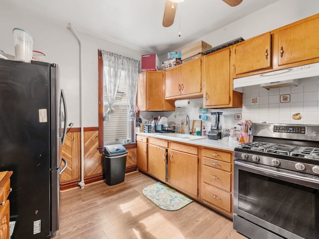 kitchen featuring tasteful backsplash, appliances with stainless steel finishes, sink, light hardwood / wood-style floors, and ceiling fan