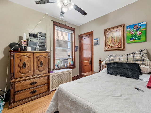 bedroom with radiator heating unit, light wood-type flooring, and ceiling fan