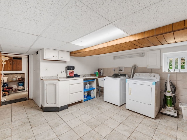 laundry room with independent washer and dryer, cabinets, and light tile patterned floors