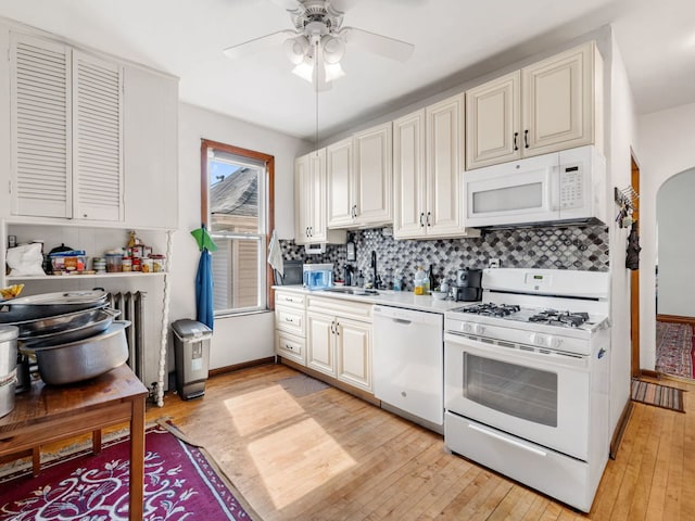 kitchen featuring sink, ceiling fan, light wood-type flooring, white appliances, and tasteful backsplash