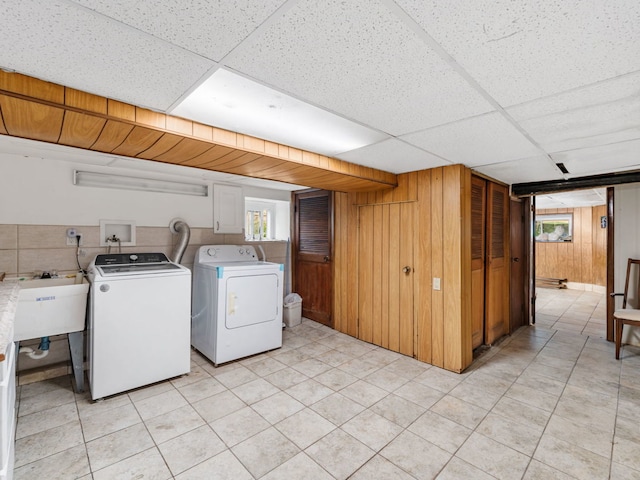 washroom featuring washer and dryer, wooden walls, sink, and light tile patterned floors