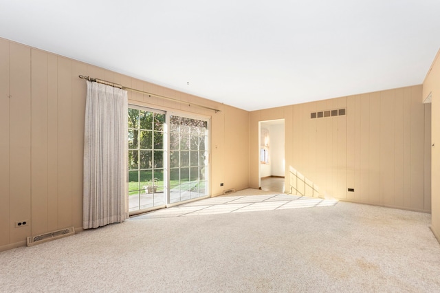 empty room featuring light carpet and wooden walls