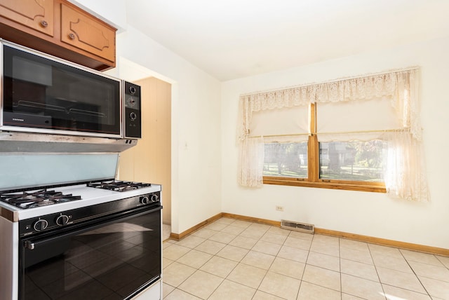 kitchen with white gas stove and light tile patterned floors