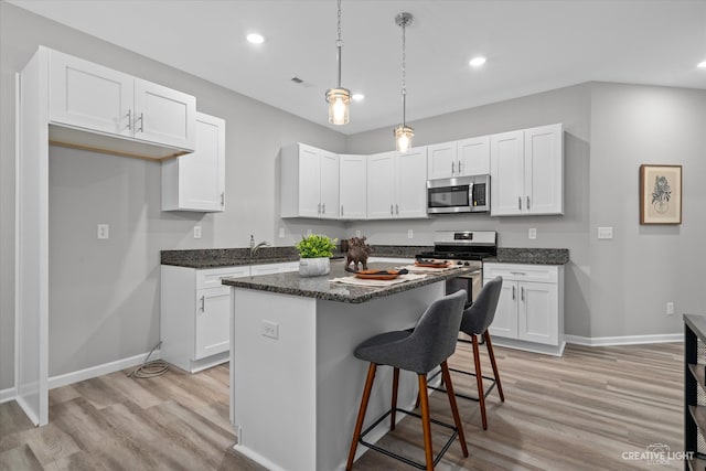 kitchen with a center island, white cabinetry, stainless steel appliances, and light wood-type flooring