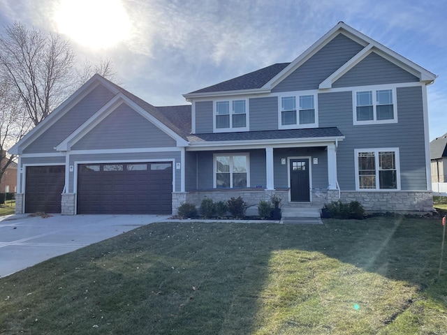 craftsman-style home featuring an attached garage, a shingled roof, a front lawn, concrete driveway, and stone siding