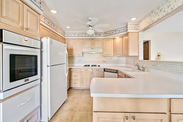 kitchen featuring light brown cabinetry, sink, kitchen peninsula, and white appliances