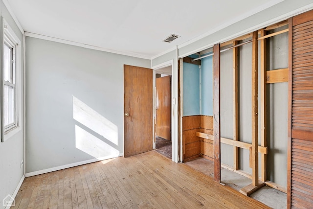 unfurnished bedroom with a closet, crown molding, and light hardwood / wood-style flooring