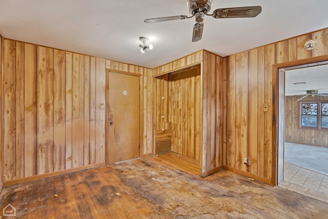 unfurnished room featuring wooden walls, dark hardwood / wood-style floors, and ceiling fan