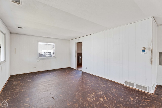 spare room with a textured ceiling and wooden walls