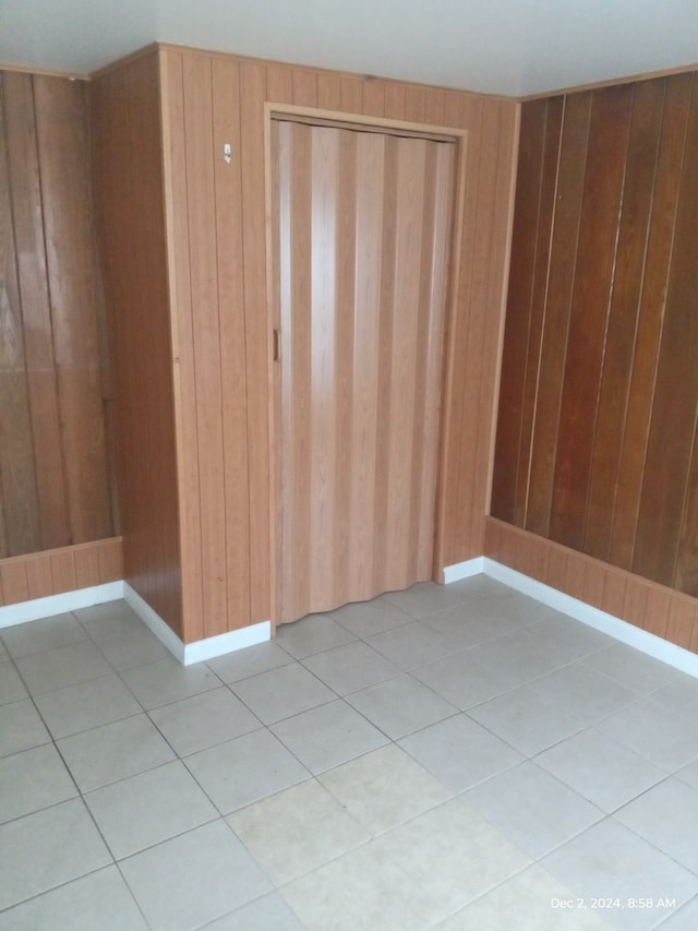 tiled spare room featuring wooden walls