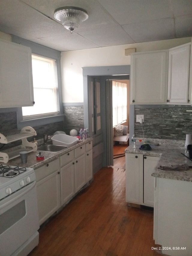 kitchen with white cabinets, white range, sink, dark hardwood / wood-style floors, and decorative backsplash