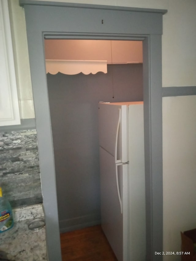 kitchen with white refrigerator and dark wood-type flooring