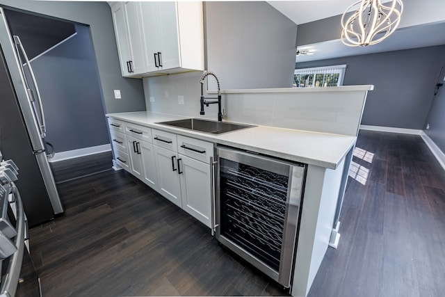 kitchen featuring sink, hanging light fixtures, white cabinetry, wine cooler, and stainless steel refrigerator