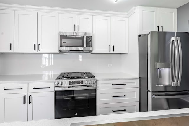 kitchen with light stone counters, appliances with stainless steel finishes, and white cabinets